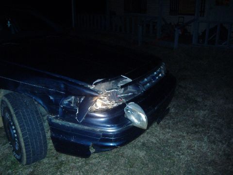 1997 Ford Crown Victoria - The front end of a dark blue 1997 Ford Crown Victoria shows significant damage to the headlight and bumper area.