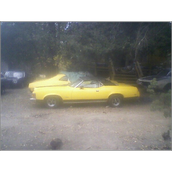Yellow 1973 Mercury Cougar convertible parked next to another car