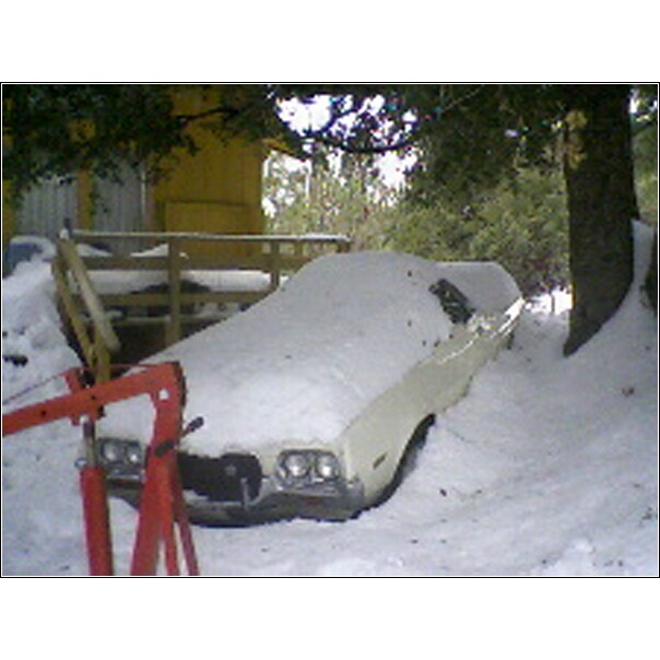 Car covered in snow with a red engine hoist in front