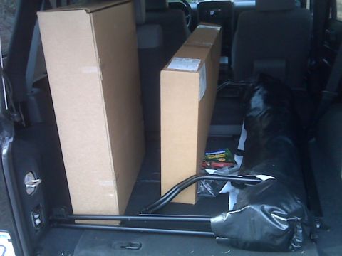 2008 Jeep Wrangler - Two large cardboard boxes and a black tarp are visible in the rear cargo area of an SUV.