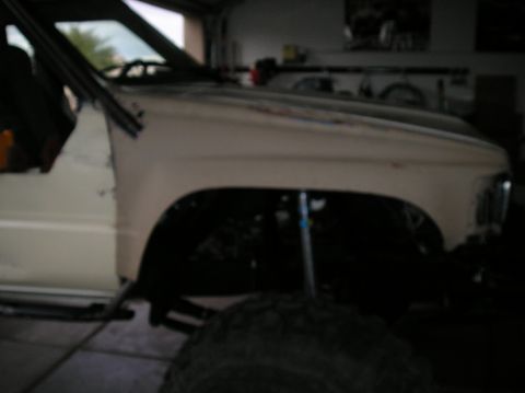 1986 Toyota Hilux - Side view of a white Toyota pickup truck's front fender and door, showing lifted suspension.