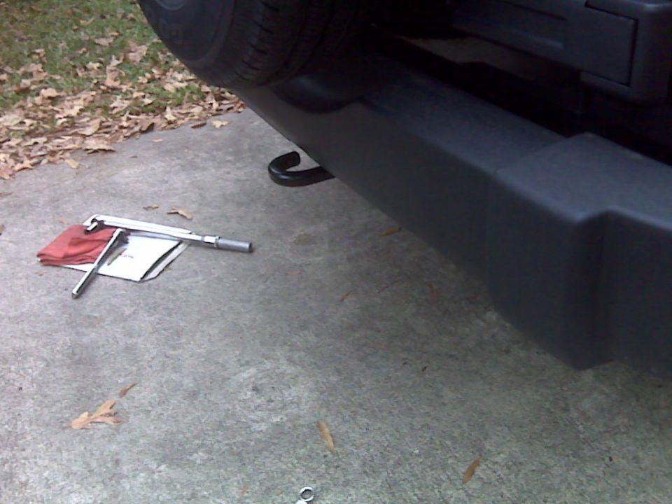Rear bumper and spare tire with jack and tools on concrete