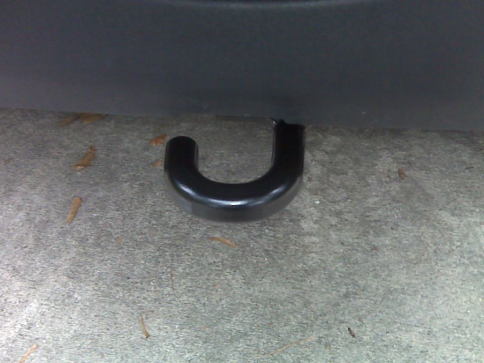 Black tow hook attached to vehicle underside, resting on concrete