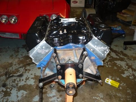 1973 Ford Ranchero - Engine assembly on a stand, with a red car visible behind it.