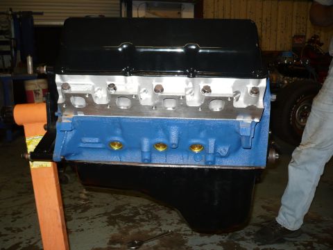1973 Ford Ranchero - Engine assembly on a stand, with a partial vehicle visible in the background.