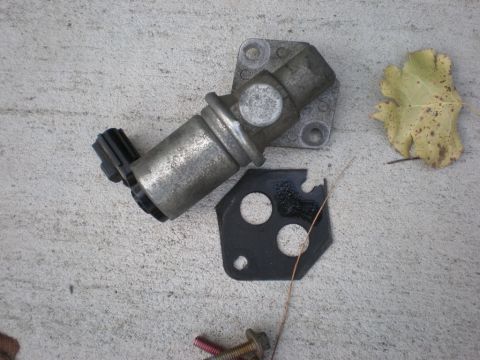 2007 Ford Mustang - Idle air control valve and gasket shown on a concrete surface.