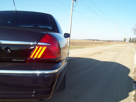 1999 Mercury Grand Marquis - Dark sedan with Mercury badging and unique taillights seen from the rear quarter on a country road.