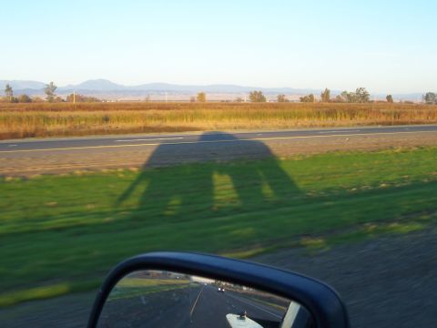 1994 Ford F-150 - Shadow of a vehicle is cast across a field next to a highway during sunset.