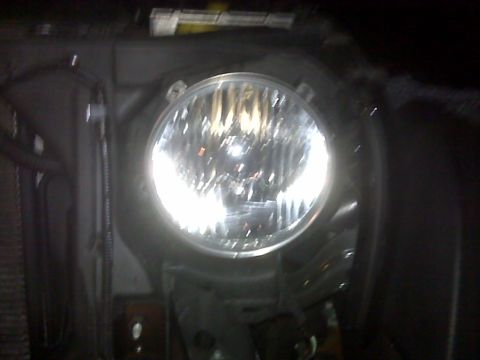 2008 Jeep Wrangler - A close-up view of a vehicle's headlight assembly, showing the bulb and surrounding mounting hardware.