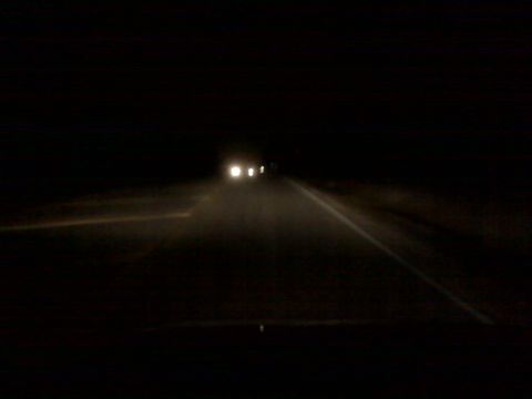 2008 Jeep Wrangler - Headlights pierce the darkness on a road at night, with multiple vehicles approaching.