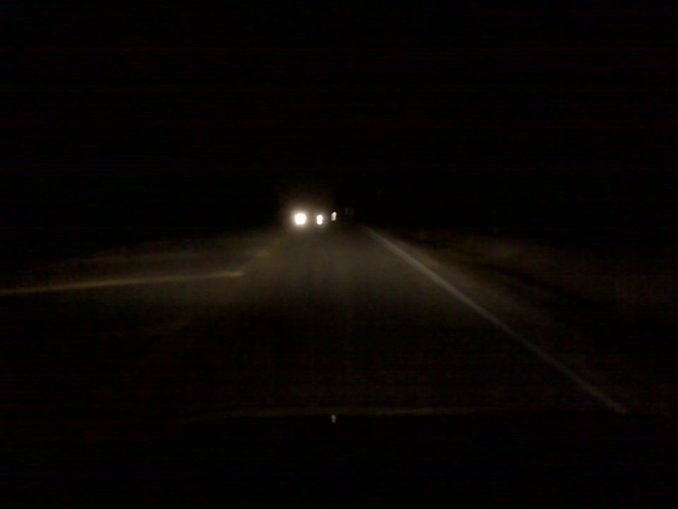 Headlights of approaching vehicles on a dark road at night