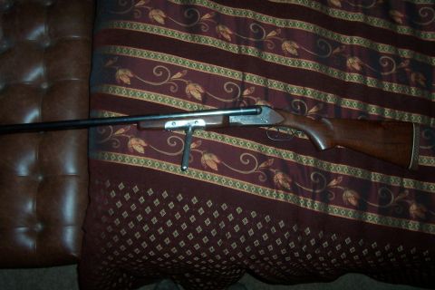 1994 Ford F-150 - A shotgun is shown resting on a patterned surface, with a leather-like material to the left.