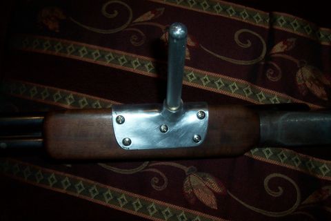 1994 Ford F-150 - Close-up of a wooden component with a metal bracket and a chrome lever, possibly a part from a vehicle or equipment.