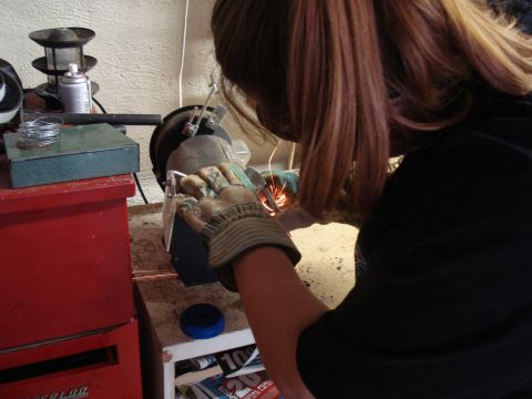 1984 Jeep J-10 - Grinding metal with a bench grinder in a workshop setting.