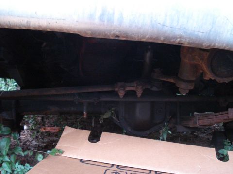 1984 Jeep J-10 - Close-up of the undercarriage, focusing on the steering linkage and suspension system of a vehicle.
