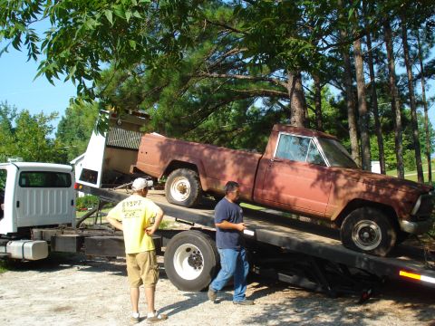 1984 Jeep J-10 - Brown Jeep J-10 pickup truck being loaded onto a flatbed tow truck with assistance from two men.
