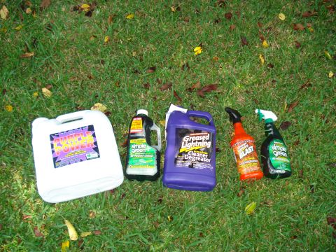 1984 Jeep J-10 - Various cleaning products are laid out on a grassy surface, including Simple Green and Greased Lightning.
