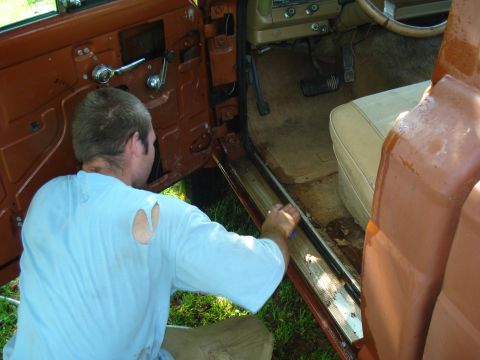 1984 Jeep J-10 - A person cleans the door jamb of a vehicle's interior, revealing the floor and seat.