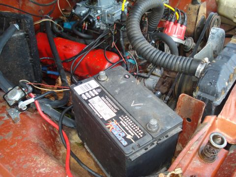 1984 Jeep J-10 - Close-up view of an engine bay, showing the battery, hoses, and engine components.