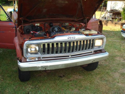 1984 Jeep J-10 - Front view of a 1984 Jeep J-10 pickup truck, hood open, revealing the engine and chrome grille.