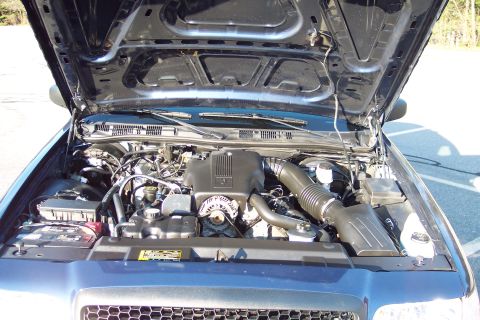 2001 Ford Crown Victoria - The engine compartment of a 2001 Ford Crown Victoria is displayed with the hood open, revealing the motor and associated parts.