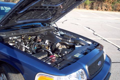 2001 Ford Crown Victoria - The engine compartment of a blue 2001 Ford Crown Victoria is displayed with the hood raised.