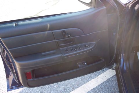 2001 Ford Crown Victoria - The interior door panel of a dark-colored vehicle, showing the window and lock controls.