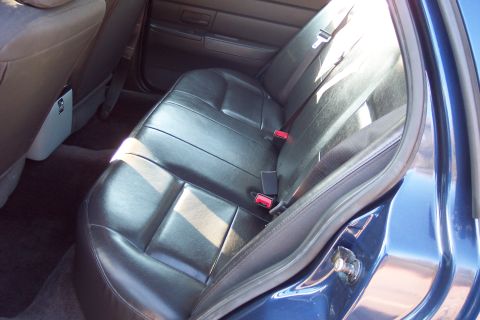 2001 Ford Crown Victoria - The interior of a 2001 Ford Crown Victoria shows black leather rear seats with sunlight streaming in.