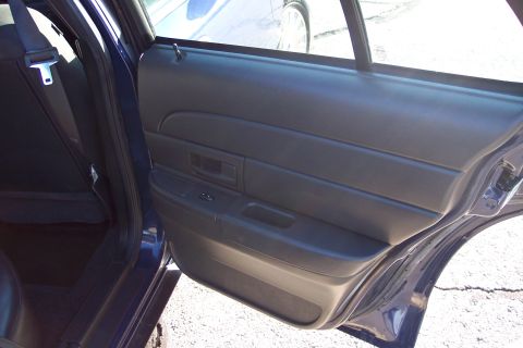 2001 Ford Crown Victoria - The interior door panel and seat of a dark blue sedan are visible.