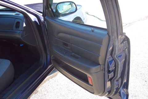 2001 Ford Crown Victoria - View of the interior door panel and dashboard of a 2001 Ford Crown Victoria, with another vehicle visible in the side mirror.