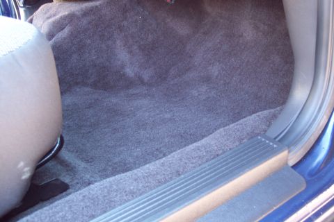 2001 Ford Crown Victoria - Close-up view of the carpeted interior floor and the base of a seat in a blue vehicle.