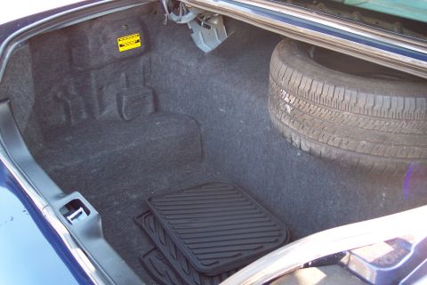2001 Ford Crown Victoria - The trunk of a blue 2001 Ford Crown Victoria contains a spare tire, floor mats, and a warning sticker.