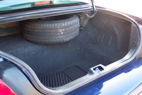 2001 Ford Crown Victoria - The spacious trunk of a 2001 Ford Crown Victoria contains a spare tire and a black rubber mat.