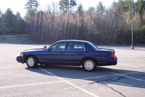 2001 Ford Crown Victoria - Side profile of a dark blue 2001 Ford Crown Victoria in an empty parking lot.