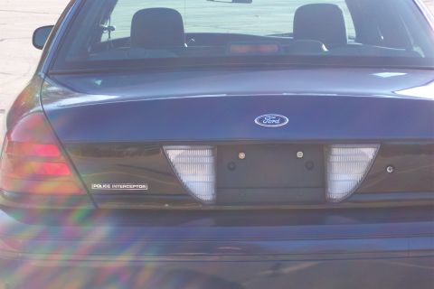 2001 Ford Crown Victoria - Rear view of a dark blue 2001 Ford Crown Victoria Police Interceptor, showing the Ford emblem and 'Police Interceptor' badging.