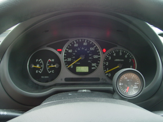 Car instrument cluster with speedometer, tach, and added aftermarket gauge