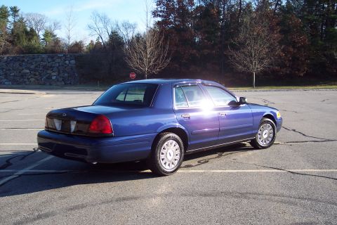 2001 Ford Crown Victoria - A blue 2001 Ford Crown Victoria is parked in an empty lot on a sunny day.