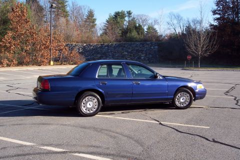 2001 Ford Crown Victoria - A blue 2001 Ford Crown Victoria is parked in an empty lot on a clear day.