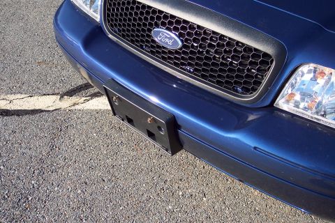 2001 Ford Crown Victoria - Close-up of the front grille and bumper of a blue Ford Crown Victoria, parked on asphalt.