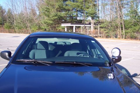 2001 Ford Crown Victoria - The interior of a police car is visible from the front, with a spotlight mounted on the driver's side mirror.
