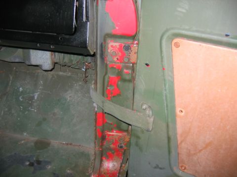 1992 Ford Mustang - Detail of a green-painted door jamb on a stripped 4x4 body, showing bolt-on upper and lower hinge plates, a fabric door check strap, and a…