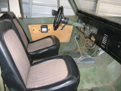 1992 Ford Mustang - Stripped-down green vintage 4x4 interior with bare painted metal floor and door panels, black-and-gray cloth bucket seats, and a thin black…