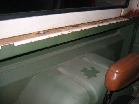 1992 Ford Mustang - Interior view of a green vehicle, showing a brown armrest and a rusted window frame.
