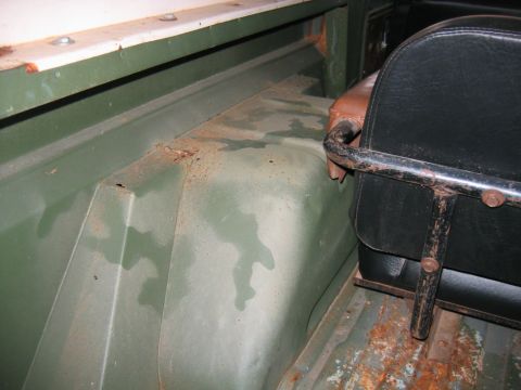 1992 Ford Mustang - Interior detail of a stripped 4x4 showing the green camouflage-painted rear wheelhouse and inner quarter panel with surface rust along the…