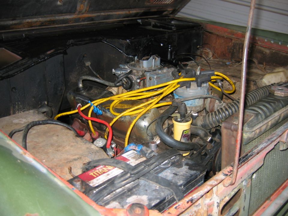Rusty engine bay with inline six, yellow spark plug wires and Titan battery