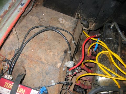 1992 Ford Mustang - Close-up view of a vehicle's engine bay, showing the battery, starter solenoid, and various electrical wiring and spark plug wires.