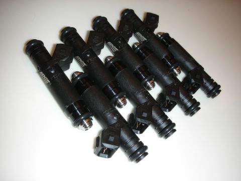 1998 Ford Crown Victoria - A set of eight black fuel injectors laid out in a row on a plain white background, each with its side electrical connector, black upper O-r…