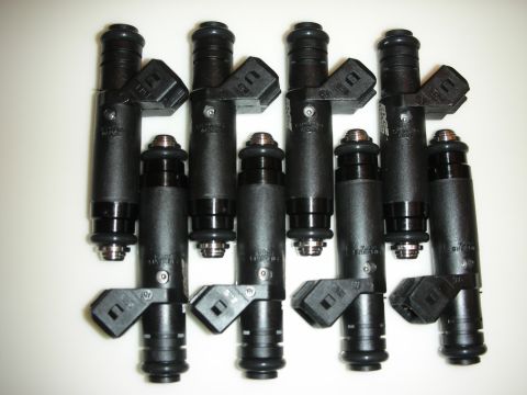 1998 Ford Crown Victoria - Eight fuel injectors are laid out on a white surface.