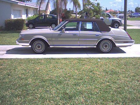 1987 Lincoln Continental - A tan 1980s Lincoln sedan with a brown vinyl roof is parked on a driveway next to a house.