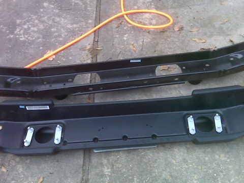2008 Jeep Wrangler - Two black Jeep Wrangler bumpers are shown laid out on concrete, with an orange hose nearby.